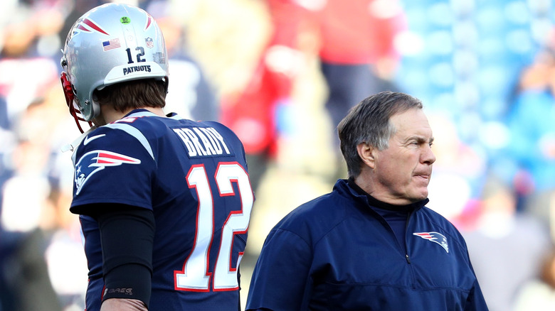 Tom Brady y Bill Belichick están espalda con espalda en el campo de fútbol